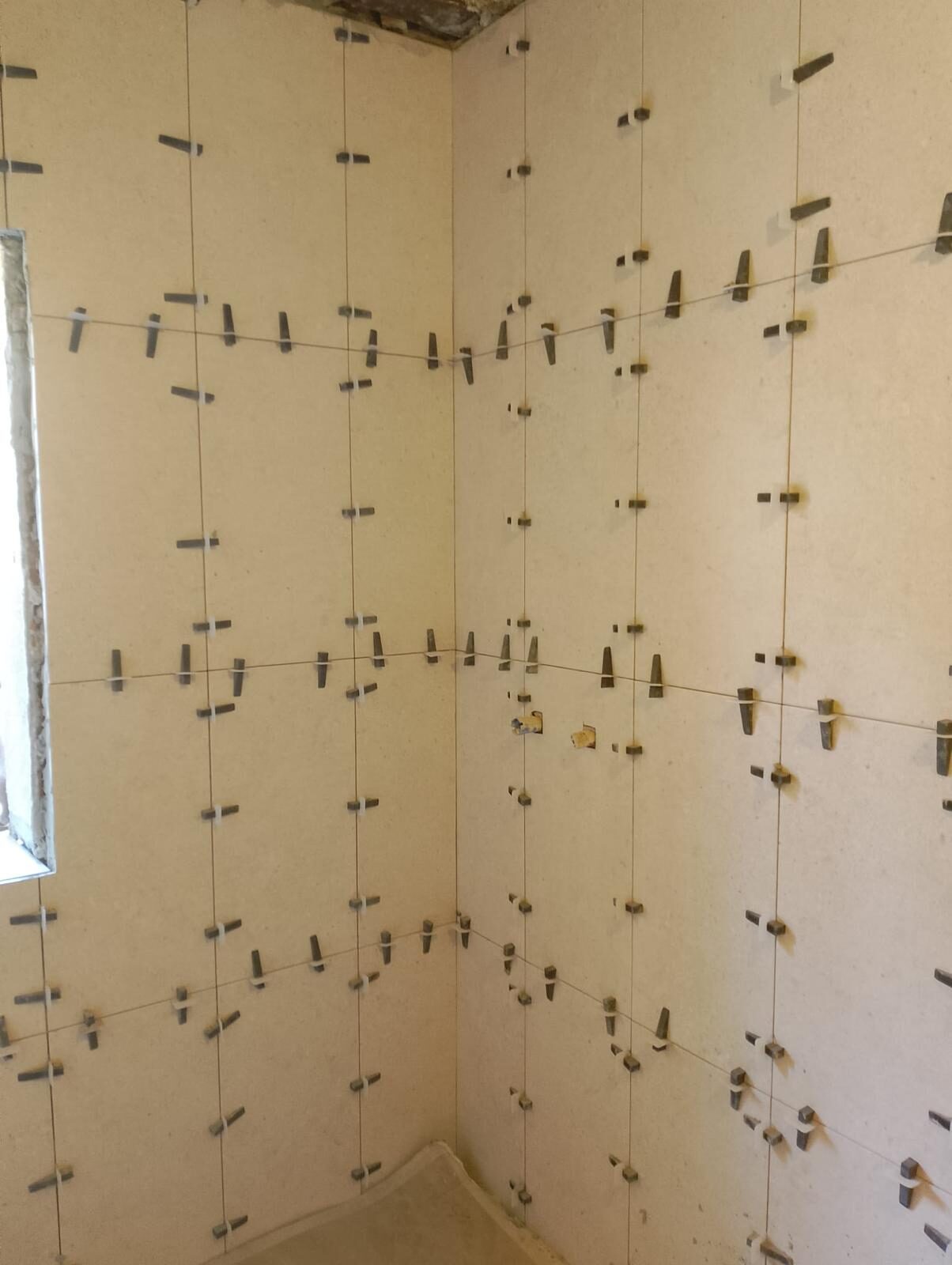 Alicatado de baño en proceso con sistema de nivelación de piezas