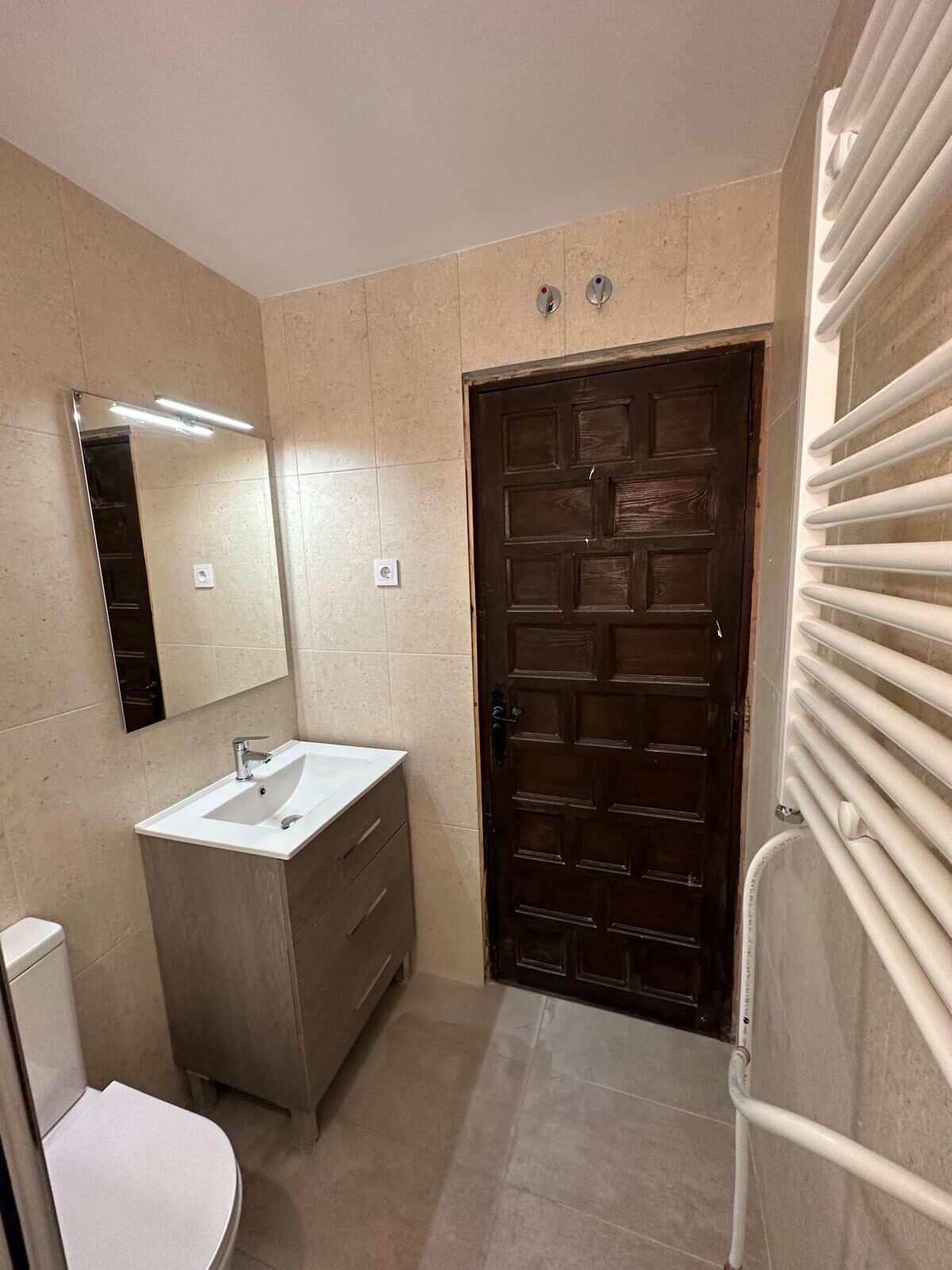 Baño reformado con mueble de lavabo, toallero radiante y carpintería restaurada