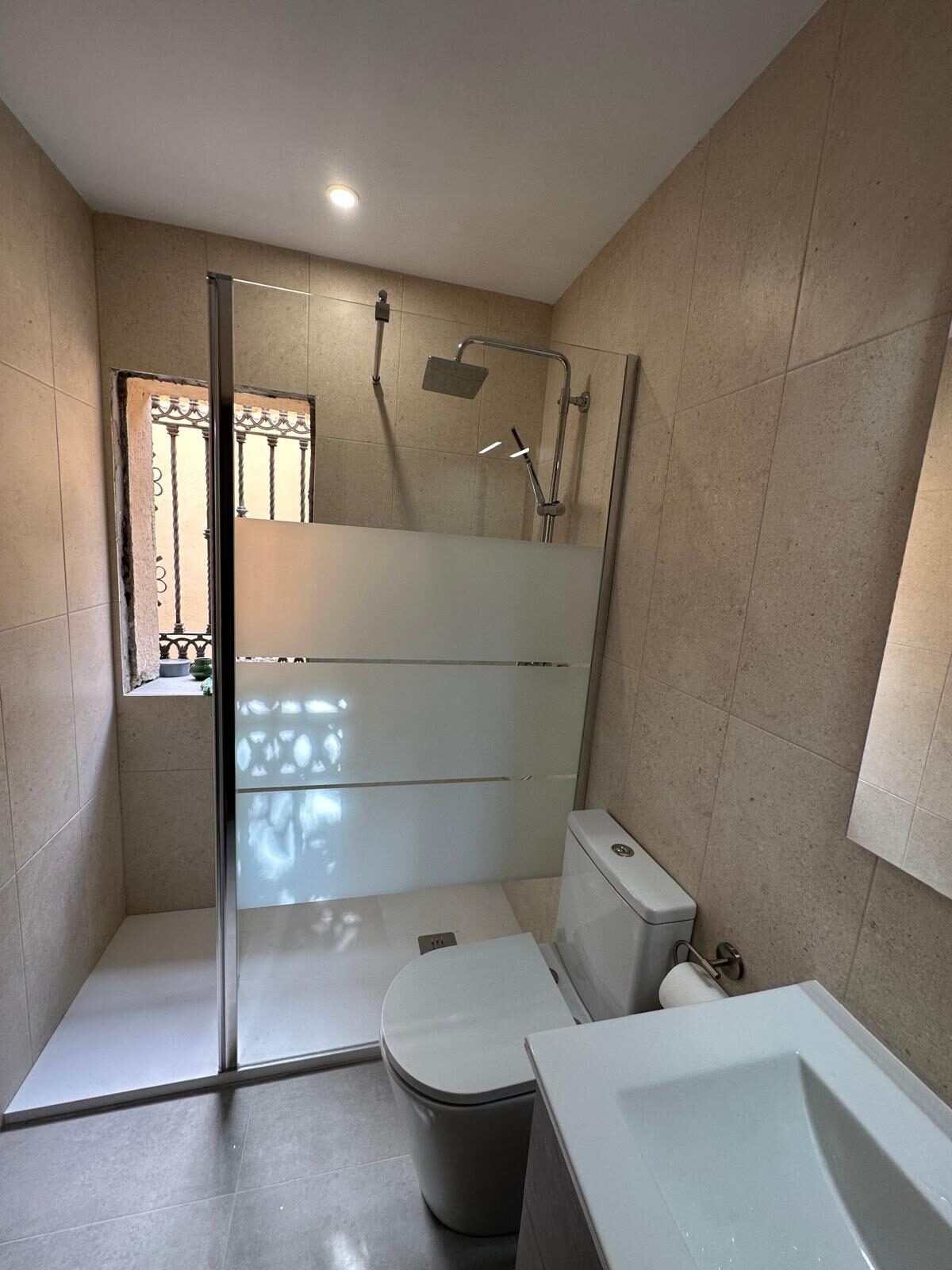 Baño terminado con ducha a ras, mampara de cristal y porcelánico beige