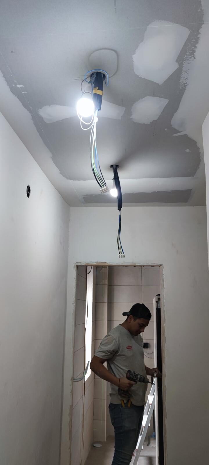 Técnico ejecutando la instalación eléctrica de un techo durante la reforma de una vivienda