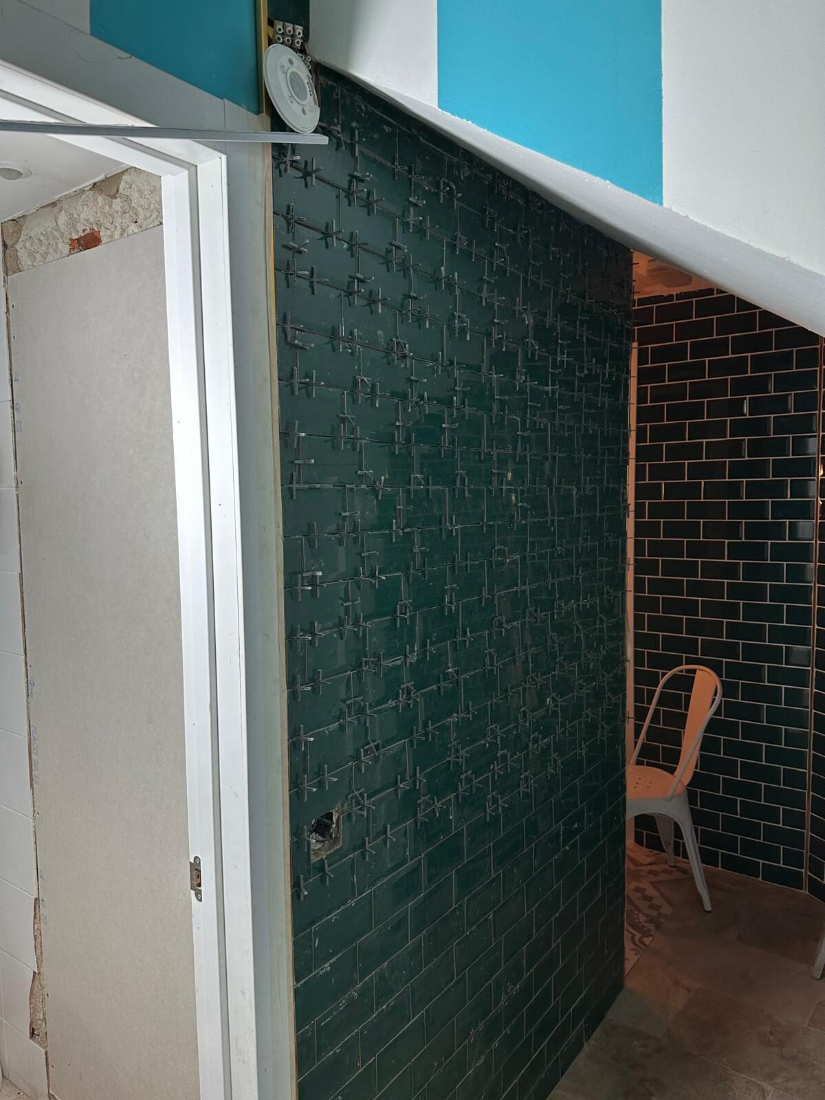 Alicatado en proceso con azulejo metro negro y crucetas de nivelación